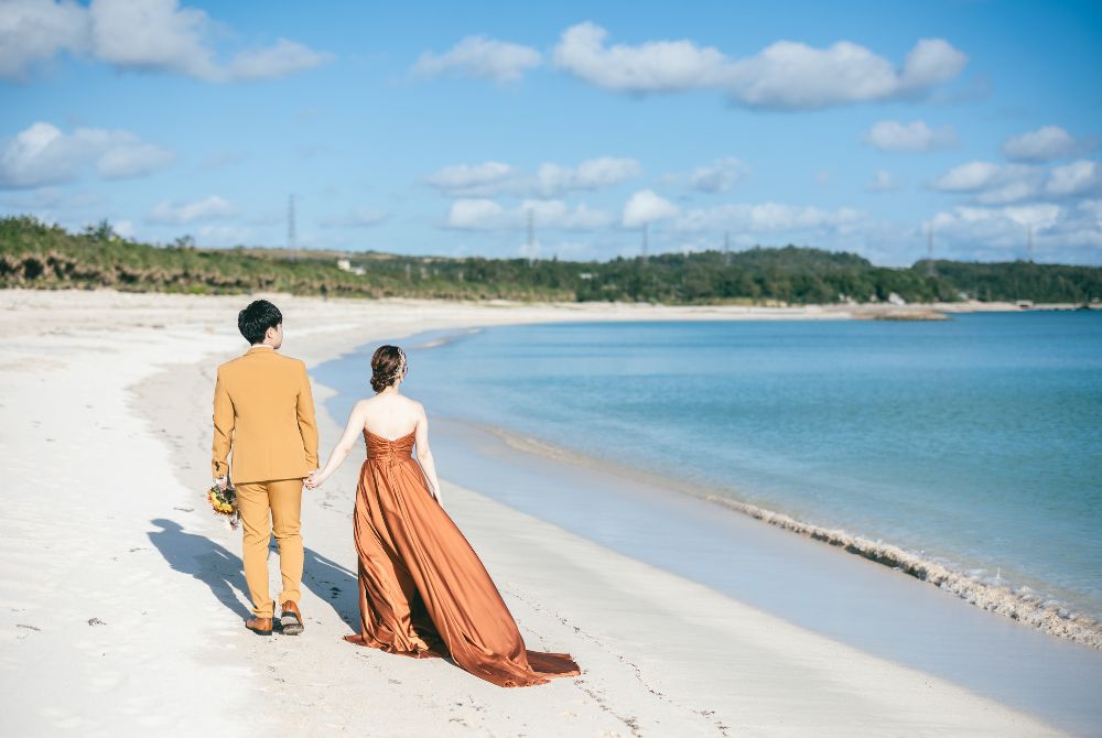 オレンジ系の衣装を身にまとったカップルビーチを歩いている