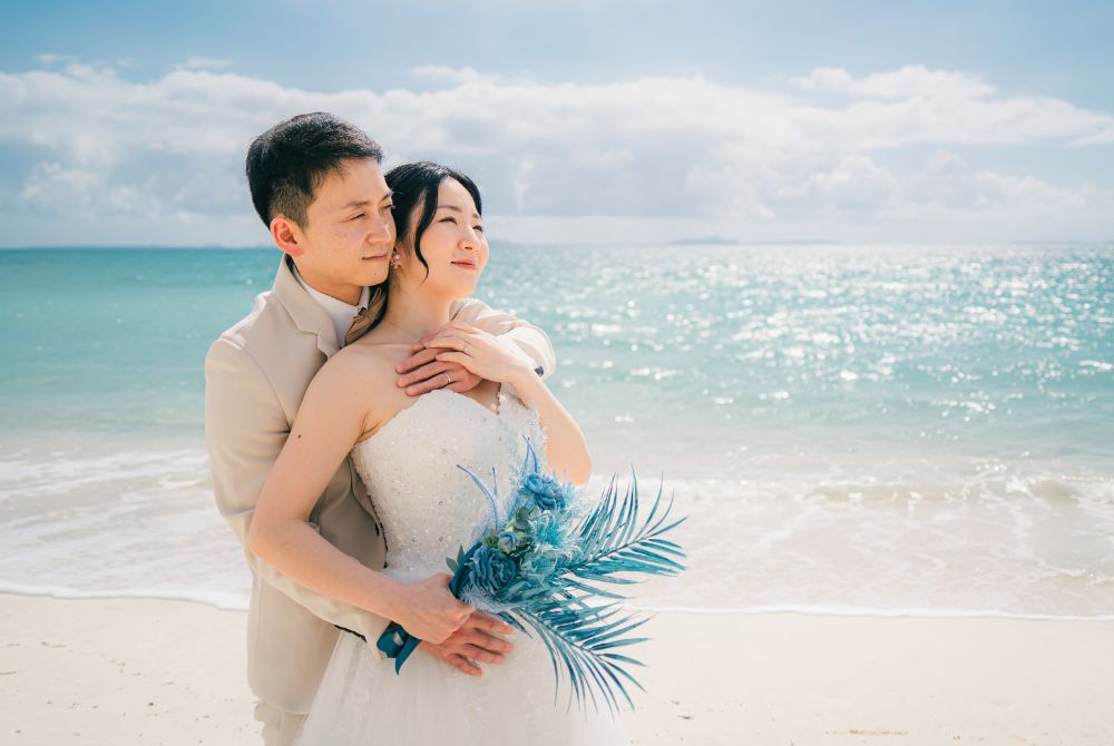 バックハグをし、ビーチを眺めるカップル