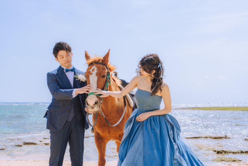 ビーチで馬をさわっているカップル様